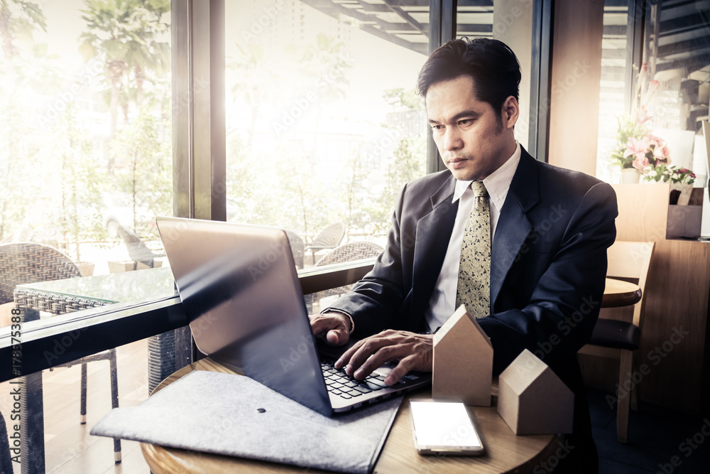 businessman working outside office eith laptop in background of coffeeshop