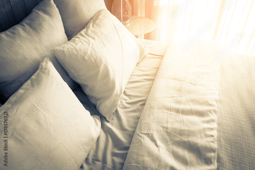 Bed maid-up with clean white pillows and bed sheets in beauty room. Close-up. Lens flair in sunlight