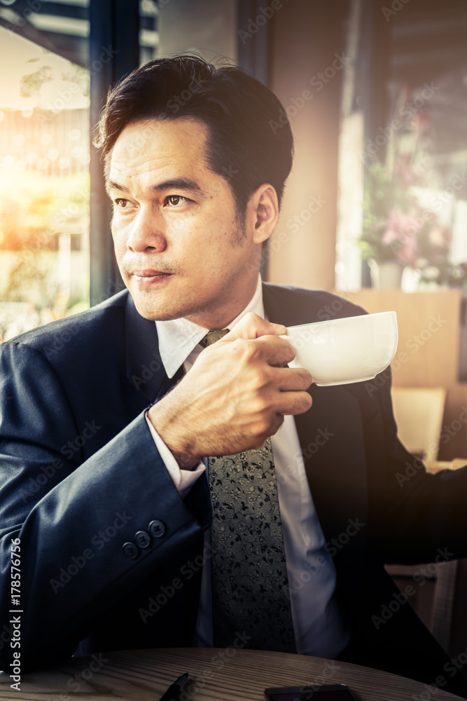 asian smart business man with coffee and newspaper morning time in coffeeshop