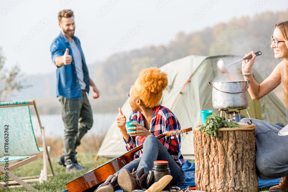 多民族朋友穿着休闲野餐，在节日期间用大锅煮汤