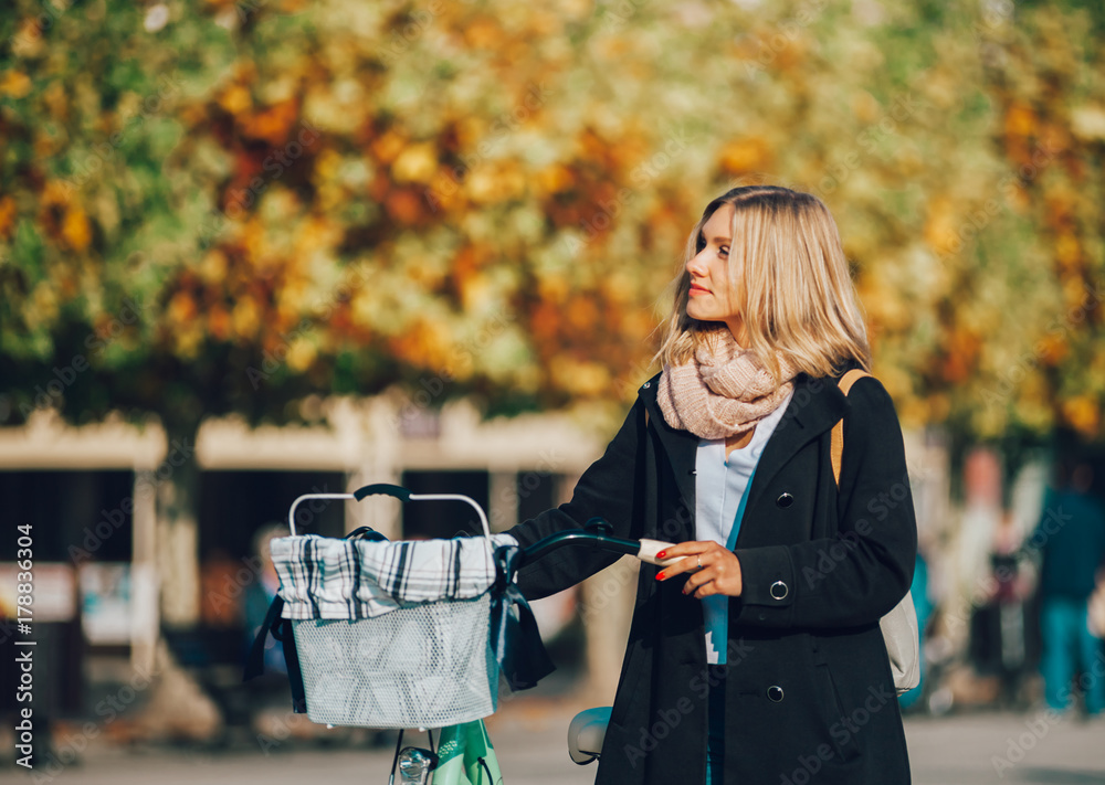 Young woman with vintage bike in the autumn city