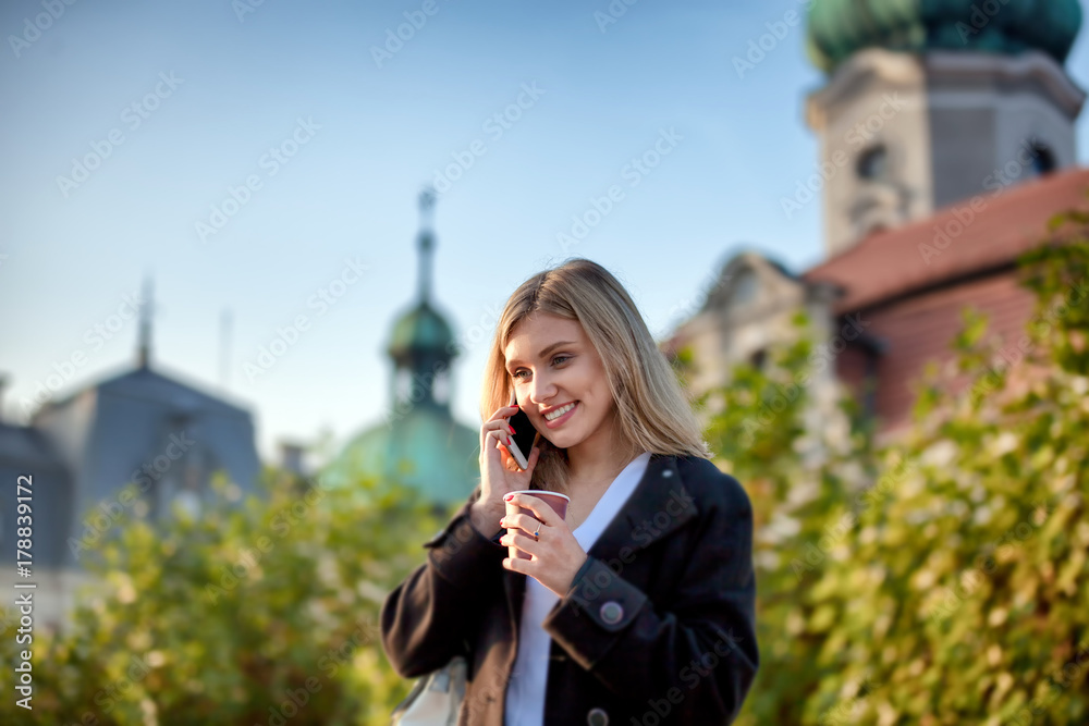 拿着咖啡杯的女孩在电话里聊天，走在街上