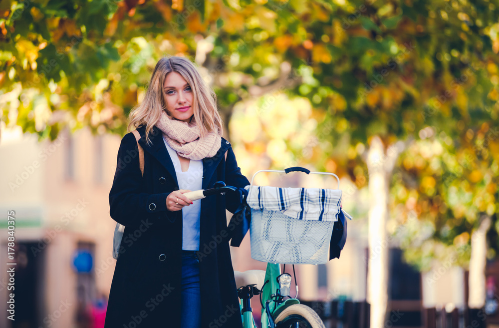 Woman with bike in urban scenery during autumn