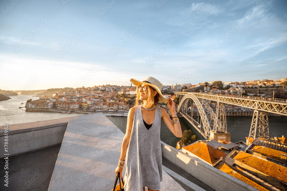 Portrait of a young smiling woman tourist walking on the beautiful cityscape background during the s