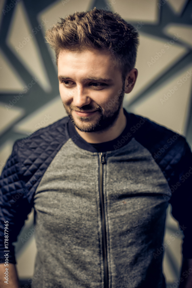 A handsome bearded man smiles and looks away. Studio portrait.