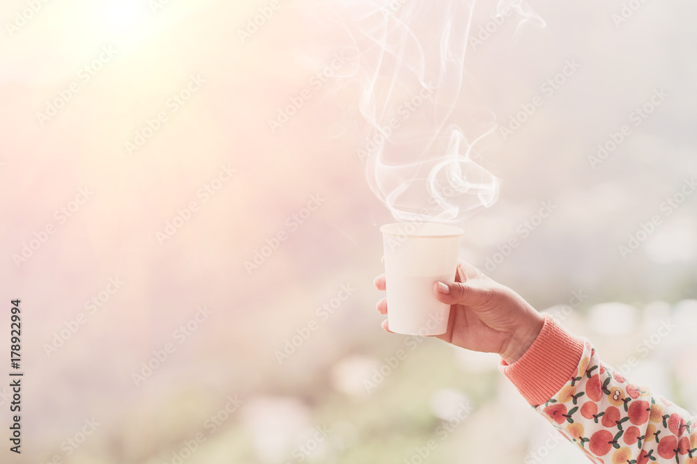 戴着手套的女性拿着热茶或咖啡的杯子。茶歇时间。冬季和旅游时间概念