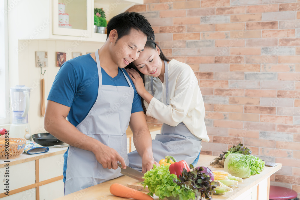 一对年轻的亚洲情侣在厨房的柜台上一起准备食物。幸福的情侣概念。