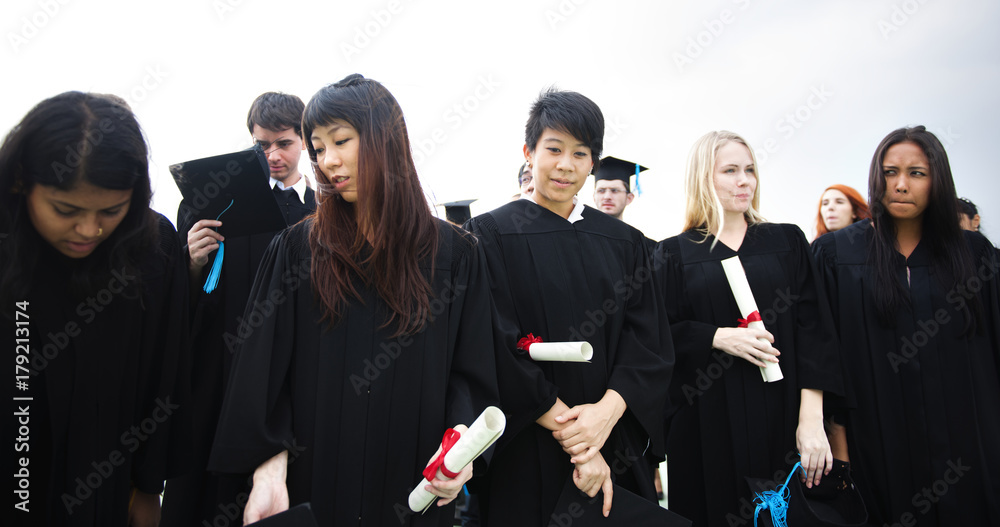 Group of diverse grads with caps and gowns in graduation ceremony