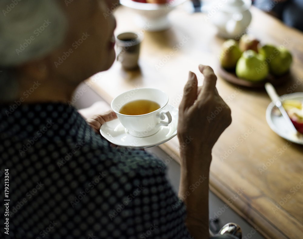 亚洲资深女性拿着茶杯与朋友交谈的背影