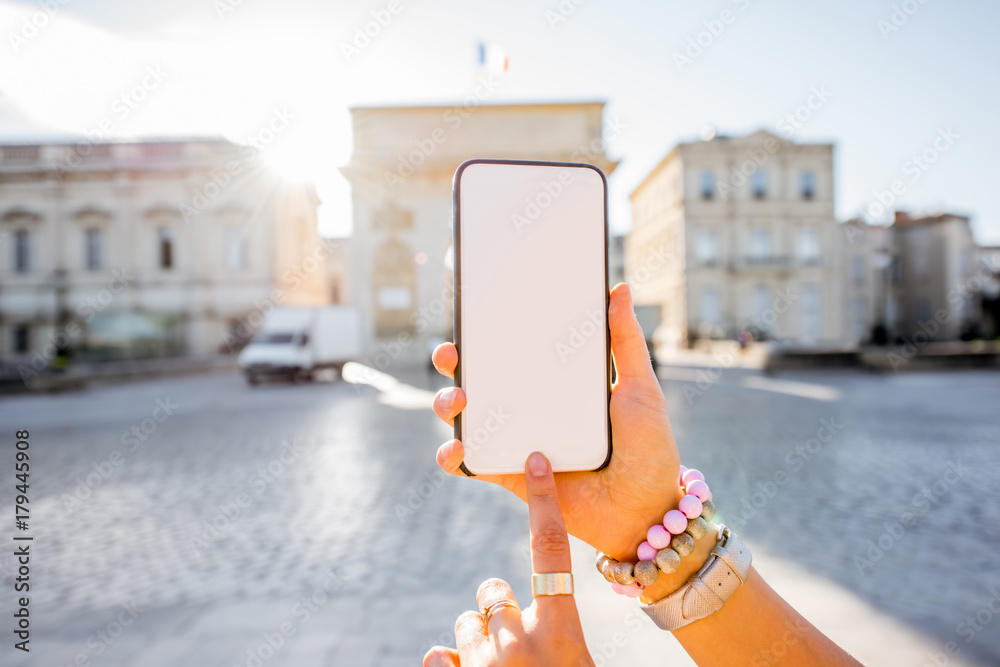 Holding a smartphone with empty screen with copy space on the old city background in Montpellier, Fr