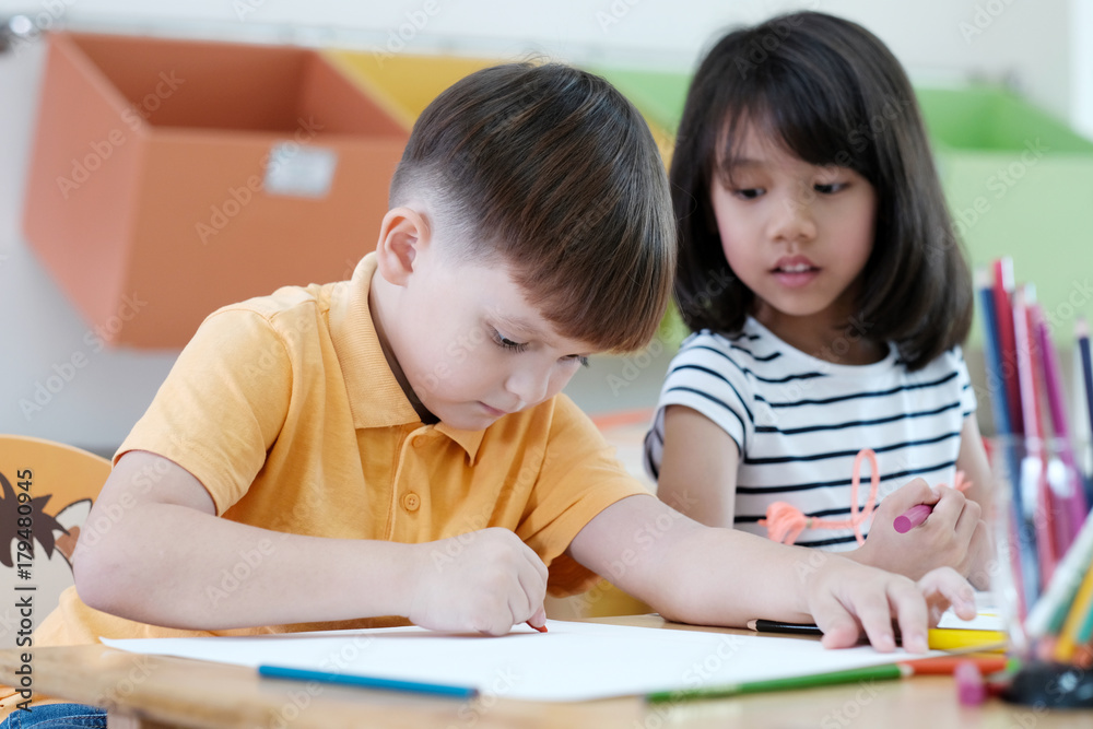 幼儿园课堂上的男孩和女孩画彩色铅笔，学前教育和儿童教育理念