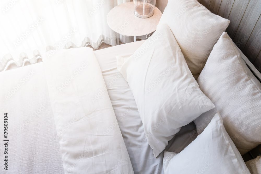 Bed maid-up with clean white pillows and bed sheets in beauty room. Close-up. Lens flair in sunlight