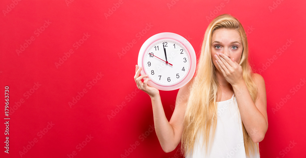 Young woman holding a clock showing nearly 12