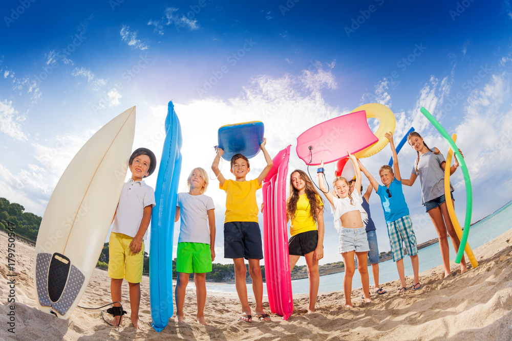 Many kids with mattresses surf boards on the beach