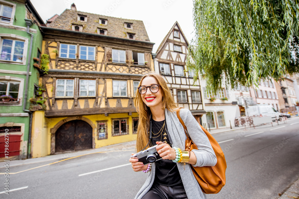 Young woman tourist standing with photo camera in front of the beautiful half-timbered houses travel