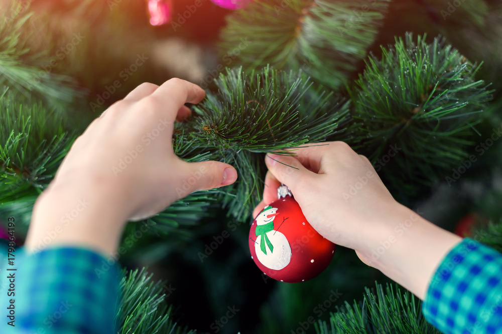 Boy hangs a Christmas tree toy