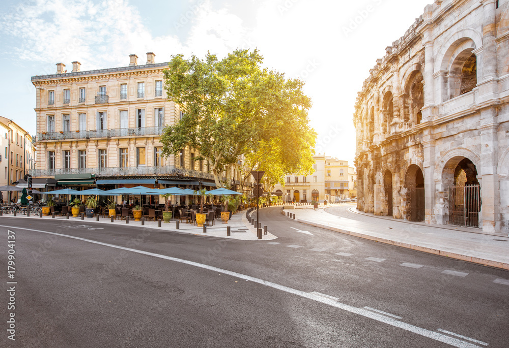 Morning street view with roman amphitheater building in Nimes city on southern france