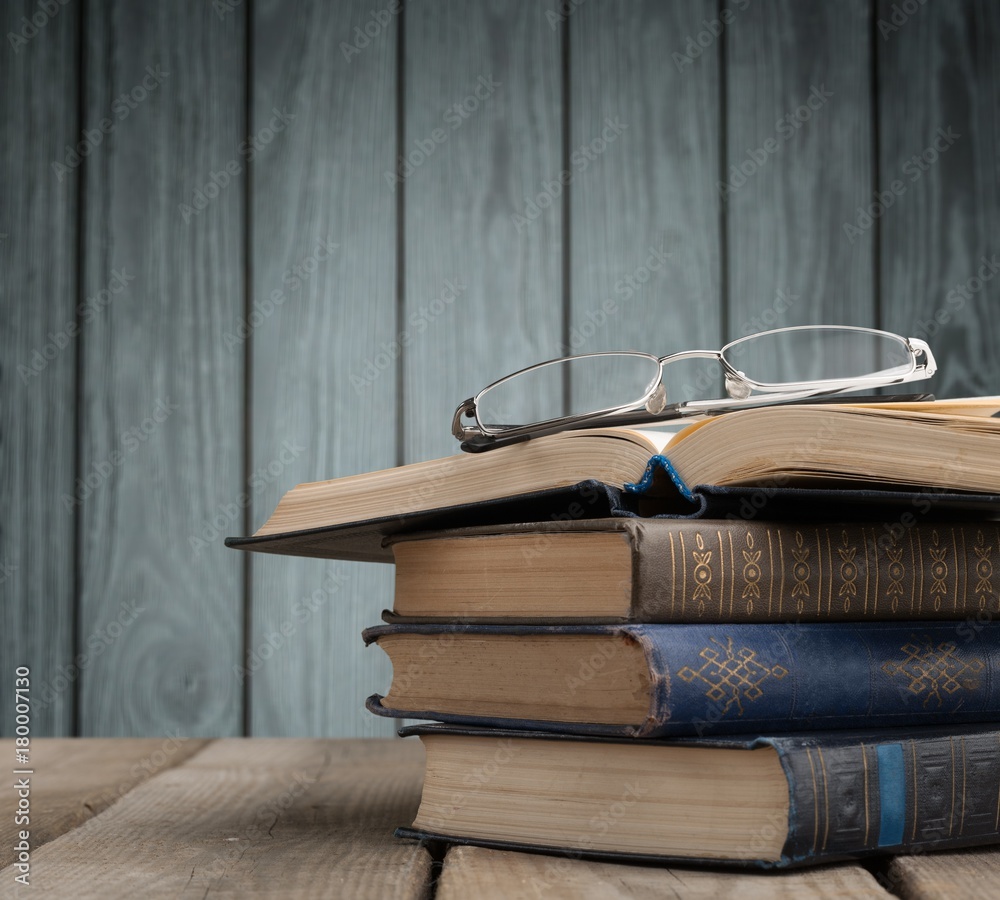 Row of old books with reading glasses above , vintage color tone