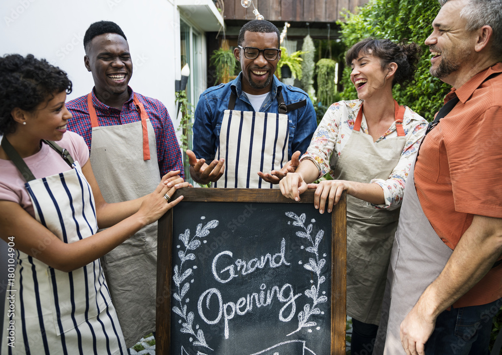 Group of diverse people with store grand opening board