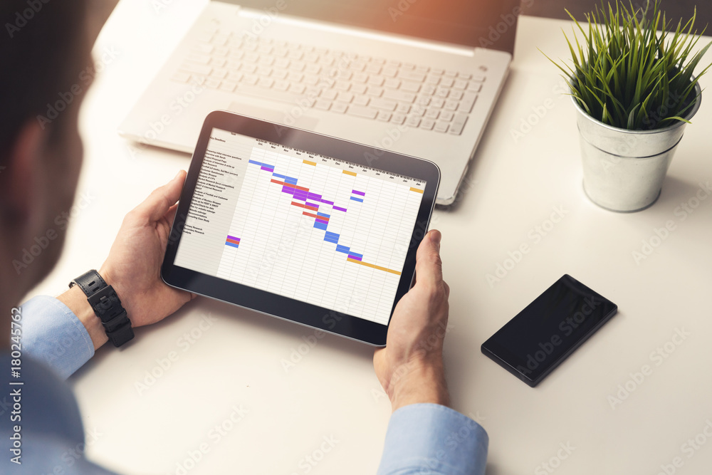 project manager looking at gantt chart on digital tablet in office