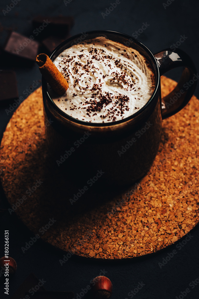 hot chocolate with cream in a dark mug on a black background