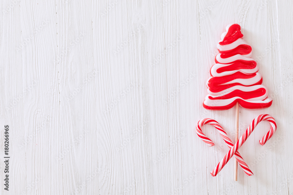 Christmas candy cane with lollipop Christmas tree over white wooden textured background