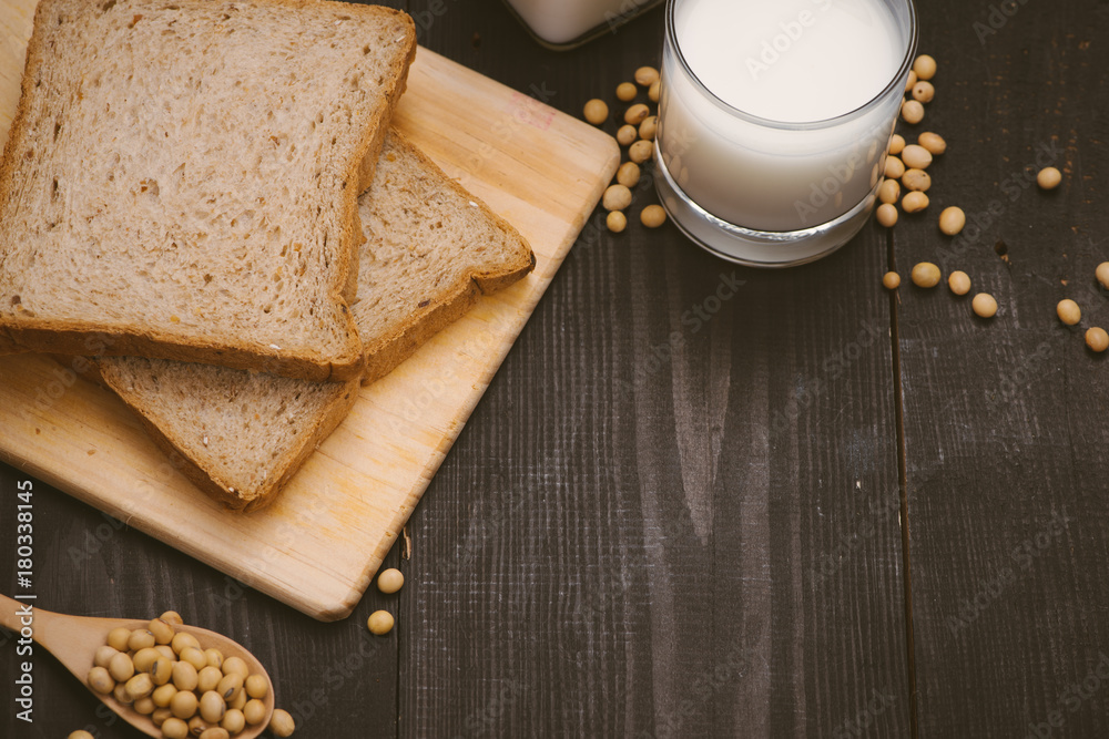 Breakfast with soy beans in spoon, soy milk and sandwich on wooden background