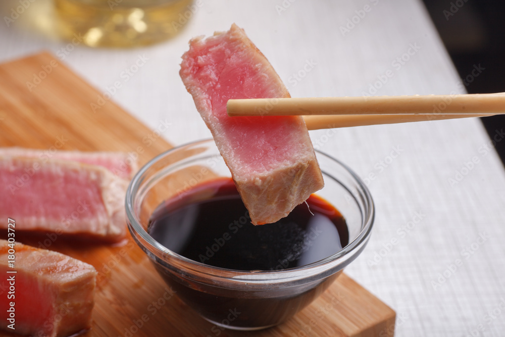 slice of tuna steak on sticks near soy sauce