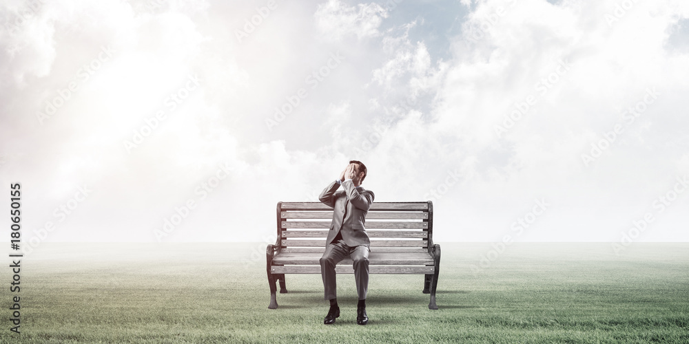 Young man in summer park on bench do not want to see anything