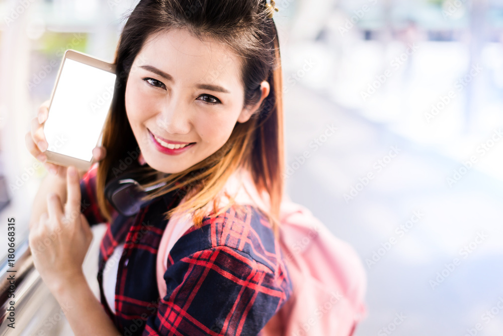 美丽幸福的年轻亚洲女孩穿着休闲服独自在火车站或机场旅行