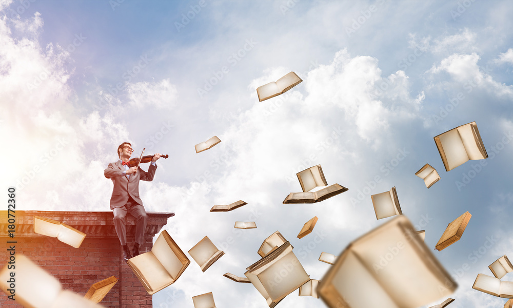 Handsome violinist play his melody and books flying around