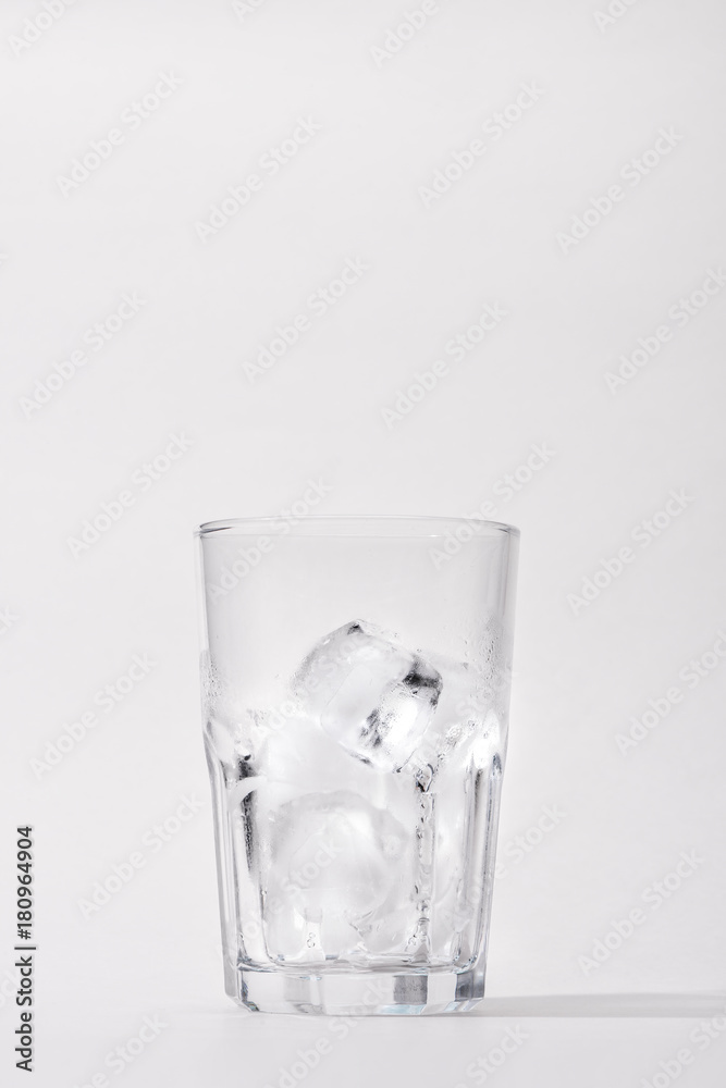 Glass with ice cubes on white background