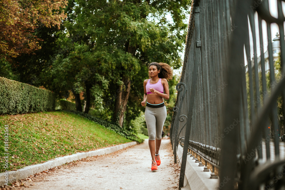 Young smiling sporty woman running in park in the morning.