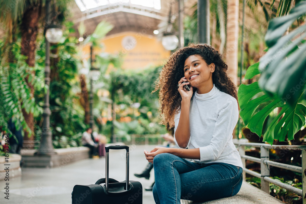 带着行李的年轻女性旅行者在打电话。