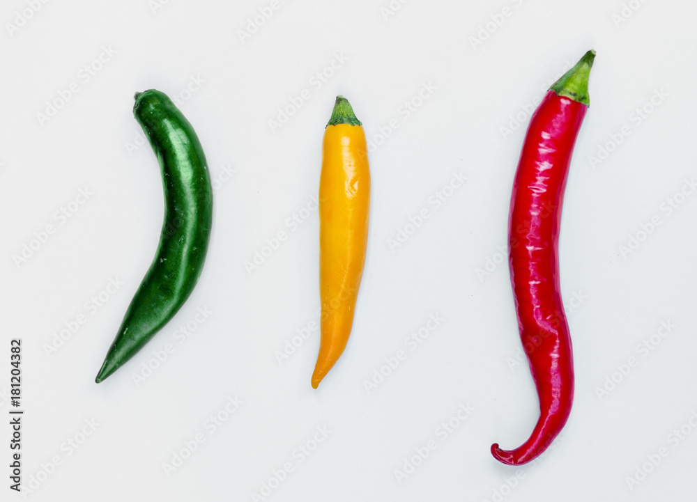 Aerial view of fresh red green yellow chili peppers on white background