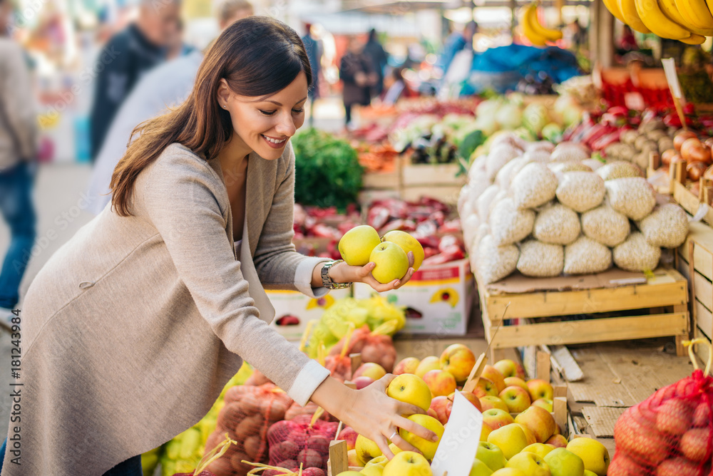 Young woman is looking for apples at green market.