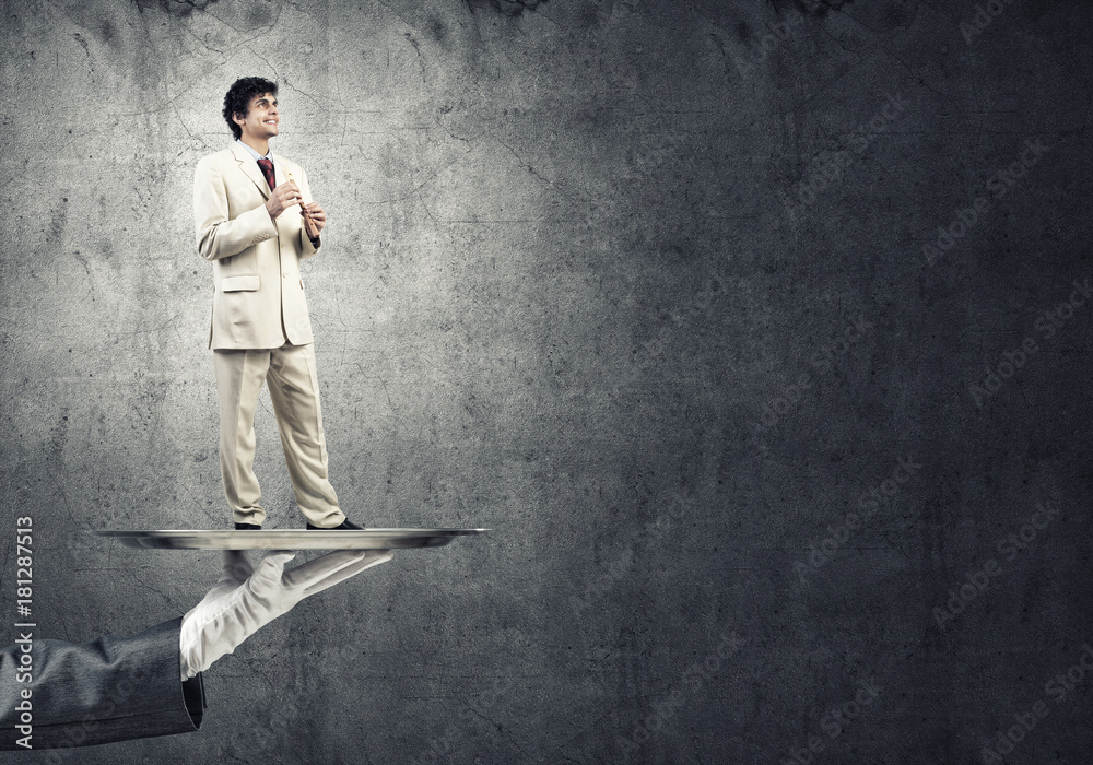 Young businessman on metal tray playing fife against concrete background