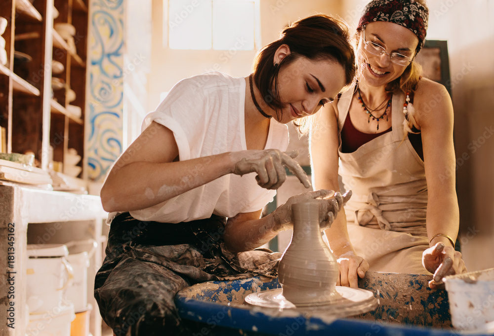 Two women at a pottery workshop making clay pots