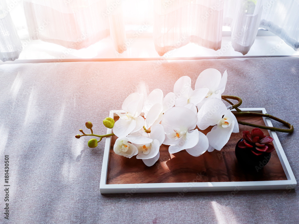 WHITE ORCHID ON WOODEN TREY WITH FABRIC BED BACKGROUND