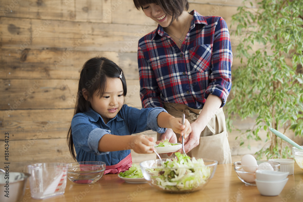 可爱的小女孩和她美丽的妈妈。他们在家的厨房里做饭时面带微笑。