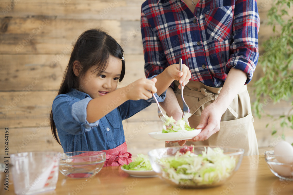 可爱的小女孩和她美丽的妈妈。他们在家的厨房里做饭时面带微笑。