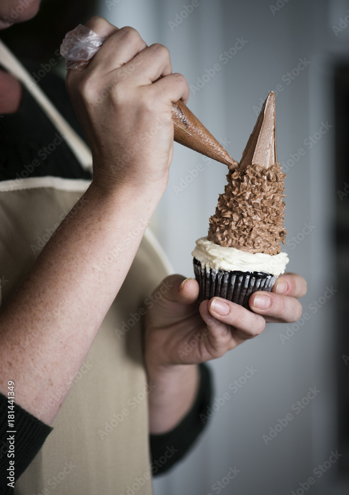 Woman decorating a cupcake