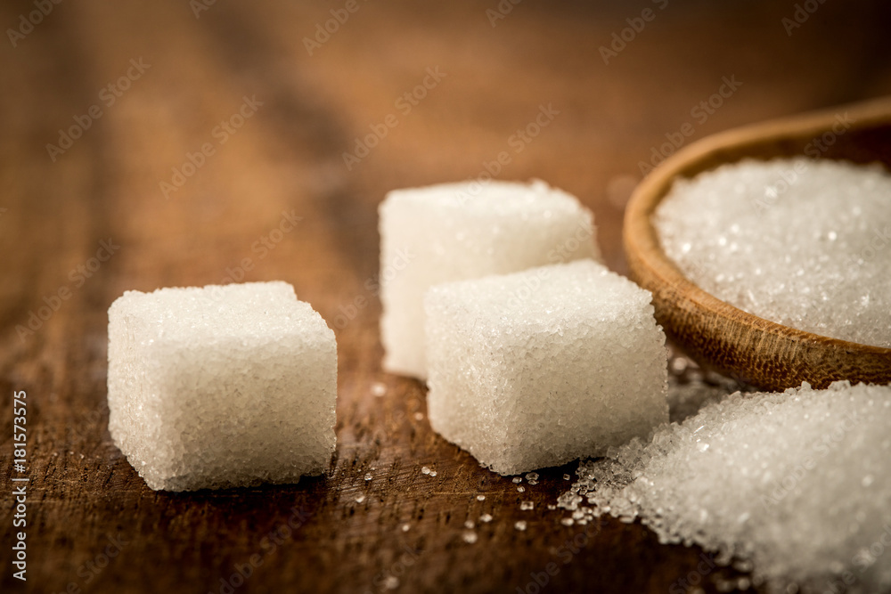 Close up a sugar cubes and cane in wooden spoon on the table ,retro color tone