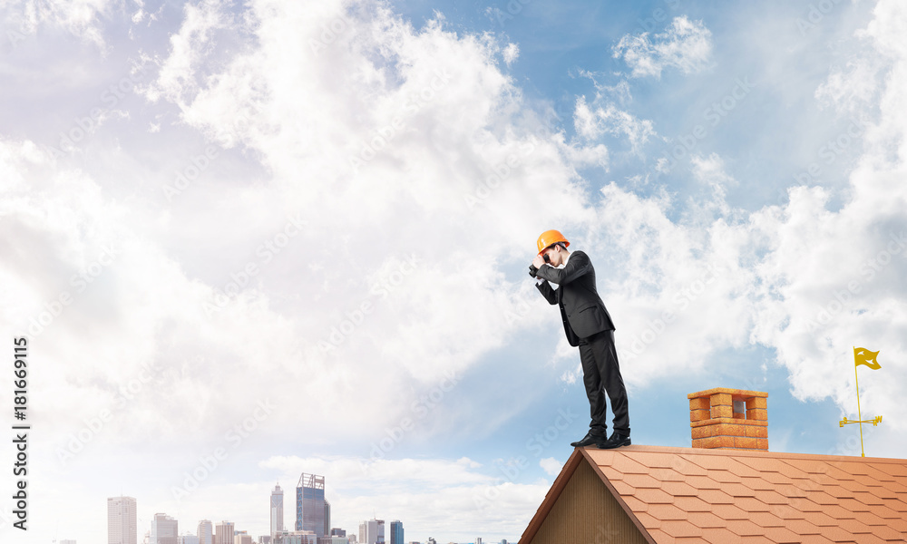 Engineer man standing on roof and looking in binoculars. Mixed media