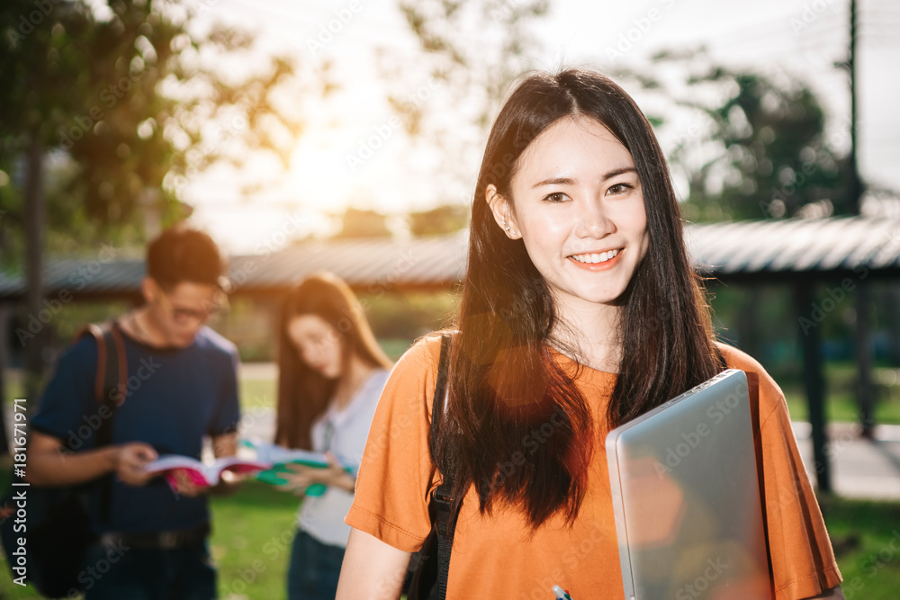 一群年轻或十几岁的亚洲学生在大学里微笑着读着书，看着ta