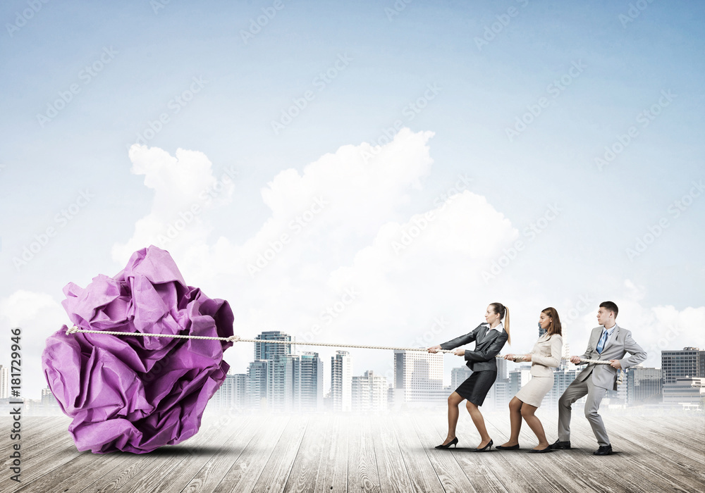 Young business people outdoors and huge paper ball as symbol of creativity