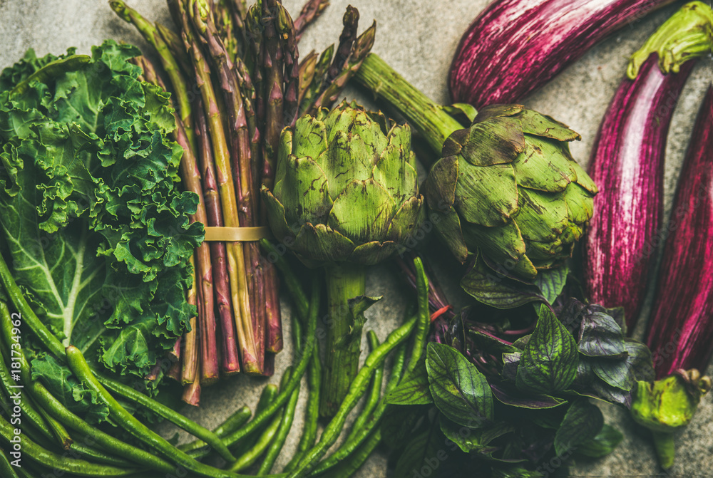 Flat-lay of green and purple vegetables over grey concrete background, top view. Local seasonal prod