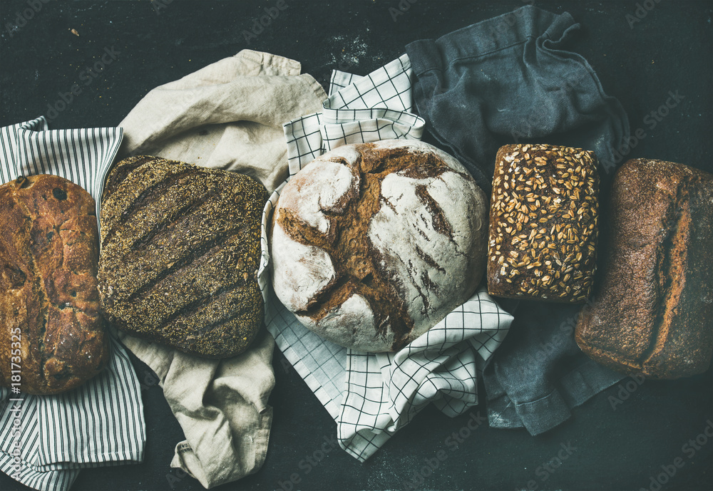 Various bread selection flat-lay. Top view of Rye, wheat and multigrain rustic bread loaves over bla