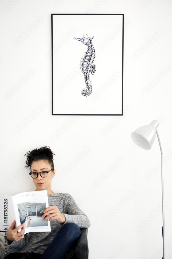 Woman relaxing with a photo frame mockup hanging on the wall