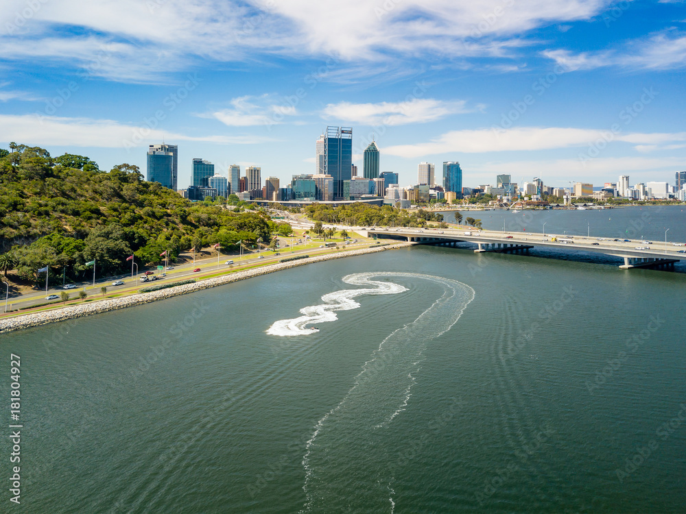 Aerial photo of Perth City and the Narrows Bridge viewed over the Swan River with a jet ski in the f